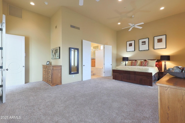 bedroom featuring ensuite bath, light carpet, a towering ceiling, and ceiling fan