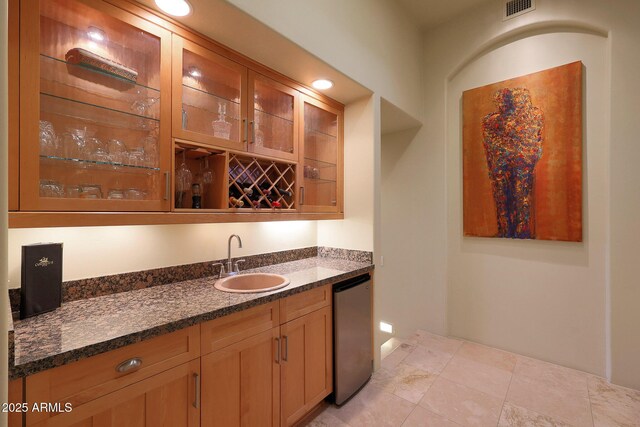 bar with stainless steel dishwasher, dark stone countertops, and sink