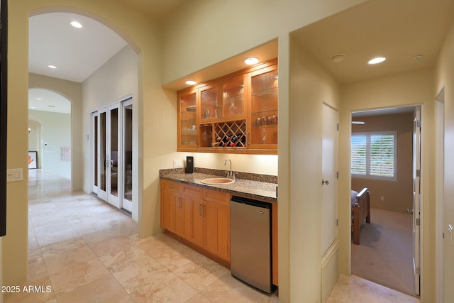 bar featuring dark stone countertops, sink, and refrigerator