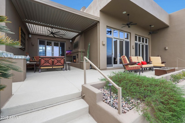 exterior space with ceiling fan, an outdoor living space with a fire pit, and a patio