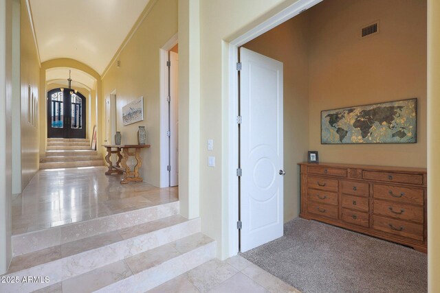 hall featuring lofted ceiling and light carpet