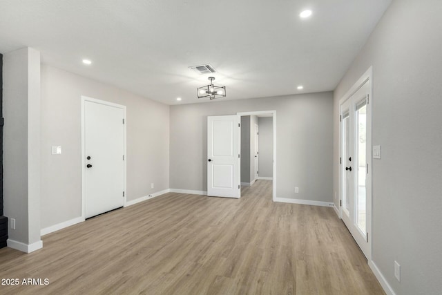 spare room with light wood-type flooring, visible vents, and baseboards