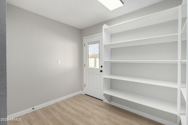 doorway featuring baseboards and wood finished floors