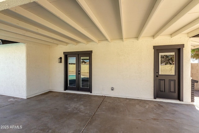 doorway to property with french doors, a patio area, and stucco siding