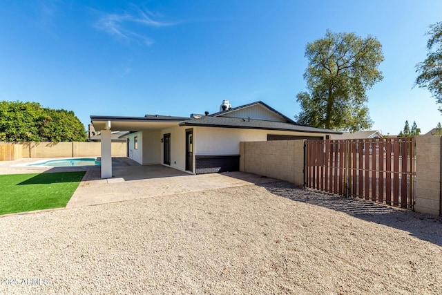 view of front facade featuring a patio, brick siding, a fenced backyard, and a fenced in pool