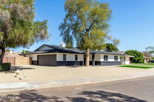 view of front facade with a garage, driveway, brick siding, and fence