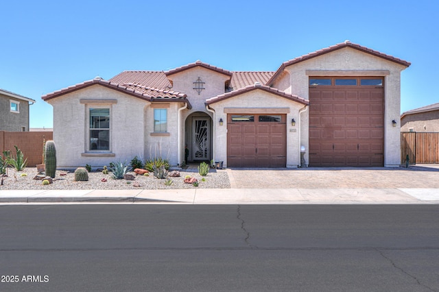 mediterranean / spanish house featuring a garage, a tiled roof, driveway, and stucco siding