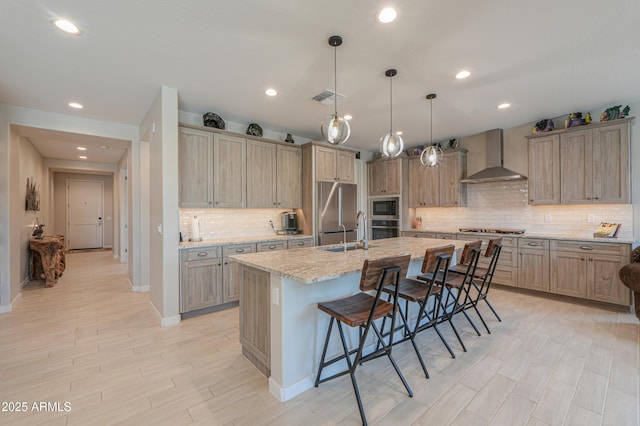 kitchen featuring backsplash, visible vents, appliances with stainless steel finishes, a breakfast bar, and wall chimney exhaust hood