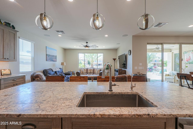kitchen with a ceiling fan, open floor plan, visible vents, and a sink
