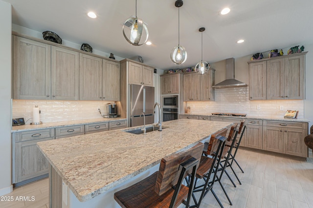 kitchen featuring wall chimney range hood, stainless steel appliances, backsplash, and a kitchen bar