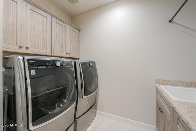laundry area with baseboards, cabinet space, and washer and dryer