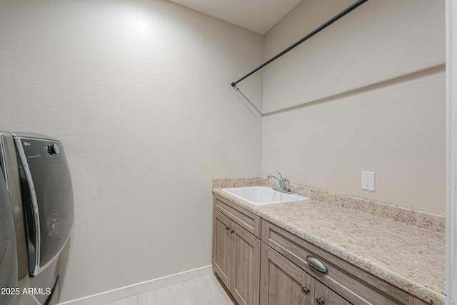 laundry area featuring a sink, baseboards, and cabinet space