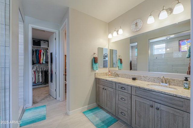 full bath featuring double vanity, a sink, baseboards, and a walk in closet