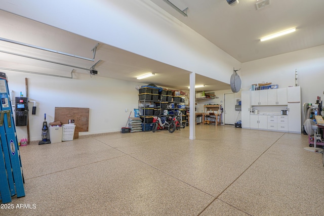 garage featuring visible vents and freestanding refrigerator