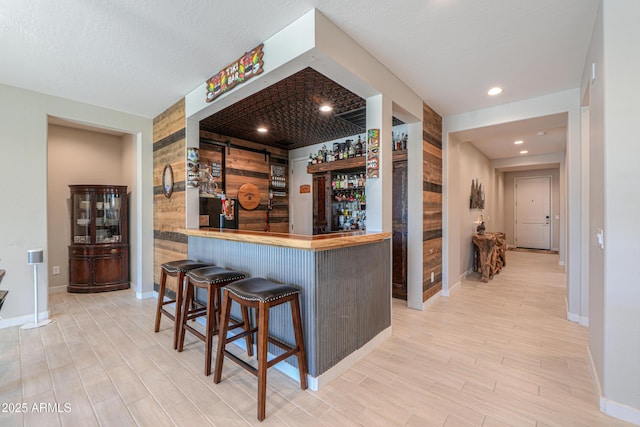 bar with a bar, recessed lighting, baseboards, and wood finished floors