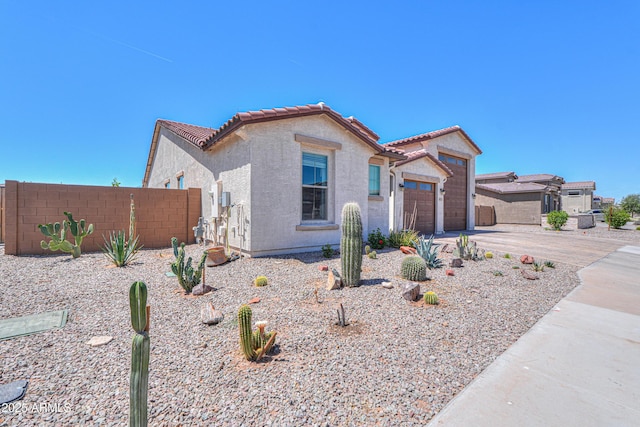 mediterranean / spanish-style home with a tiled roof, fence, concrete driveway, an attached garage, and stucco siding