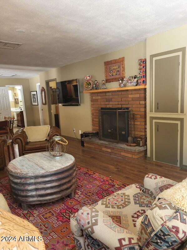 living room featuring a fireplace, wood-type flooring, and a textured ceiling