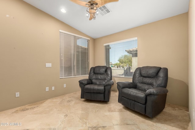 living area featuring lofted ceiling, ceiling fan, and visible vents