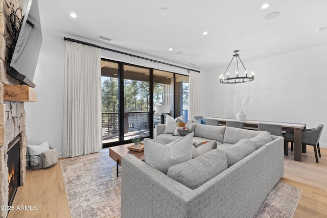living room with light hardwood / wood-style flooring, a notable chandelier, and a fireplace
