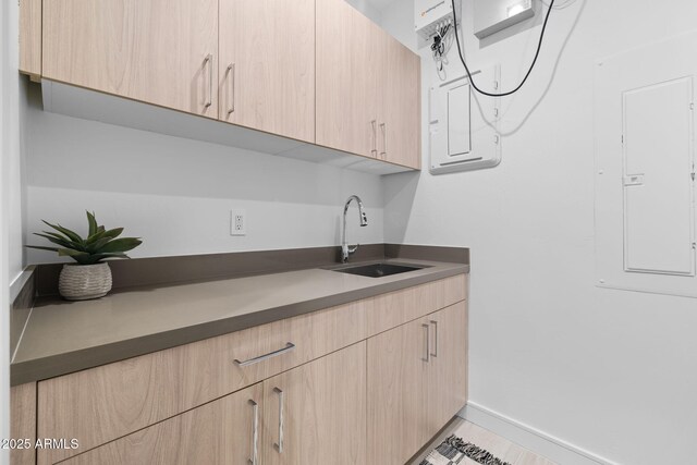 kitchen featuring light brown cabinetry, sink, and electric panel