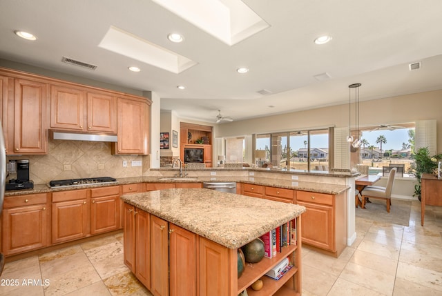 kitchen with ceiling fan, a kitchen island, sink, and hanging light fixtures