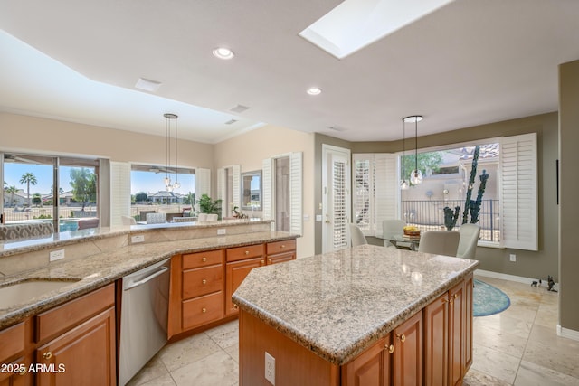 kitchen with dishwasher, sink, hanging light fixtures, light stone countertops, and a kitchen island