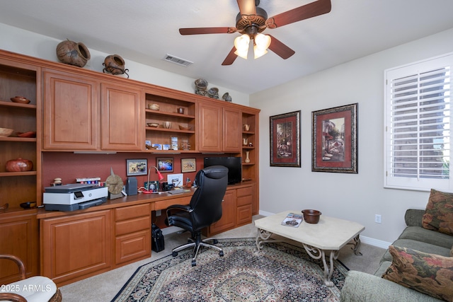 carpeted home office featuring built in desk and ceiling fan