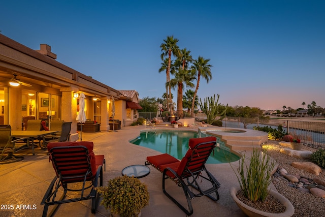 pool at dusk featuring a patio area and an in ground hot tub