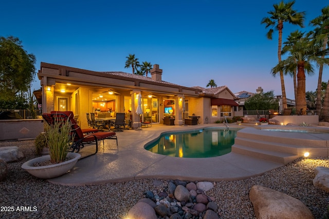 pool at dusk featuring ceiling fan and a patio area