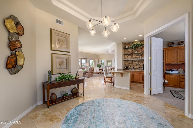 corridor featuring a raised ceiling, an inviting chandelier, and sink