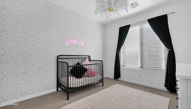 bedroom featuring carpet, an accent wall, visible vents, and baseboards