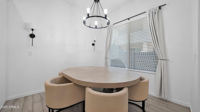 dining area with baseboards, light wood finished floors, and an inviting chandelier