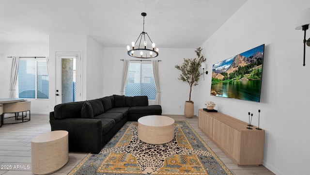 living room with a chandelier, baseboards, and light wood finished floors