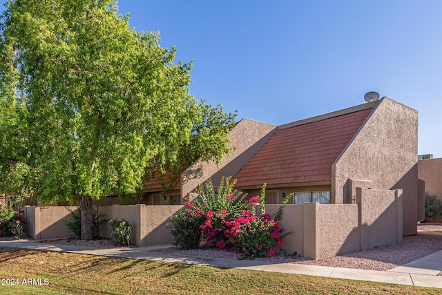 view of front of house featuring stucco siding, a fenced front yard, and a tiled roof