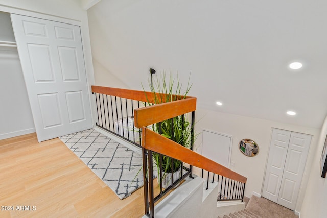 stairway with baseboards, wood finished floors, and recessed lighting