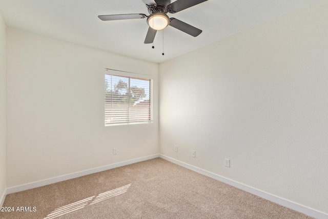 spare room featuring baseboards, a ceiling fan, and light colored carpet