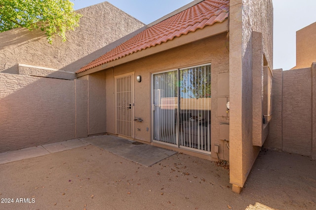 exterior space with a tile roof, a patio area, fence, and stucco siding