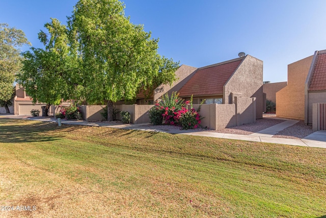 view of front of home with fence, a front lawn, and stucco siding