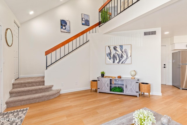 interior space with baseboards, visible vents, high vaulted ceiling, and wood finished floors