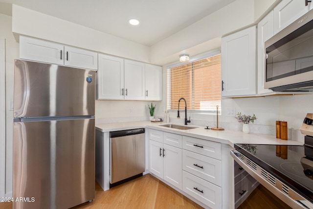 kitchen featuring appliances with stainless steel finishes, light countertops, a sink, and white cabinetry