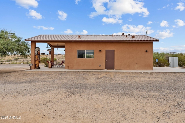 rear view of property with metal roof, a patio, and stucco siding