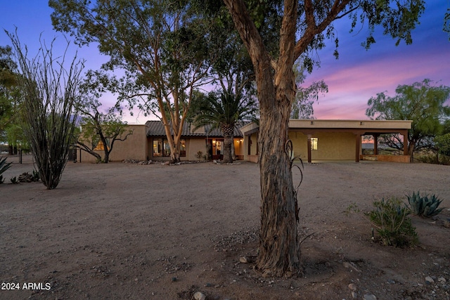 view of front facade featuring driveway, a carport, and stucco siding