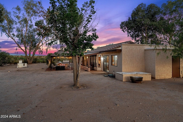 back house at dusk featuring a patio