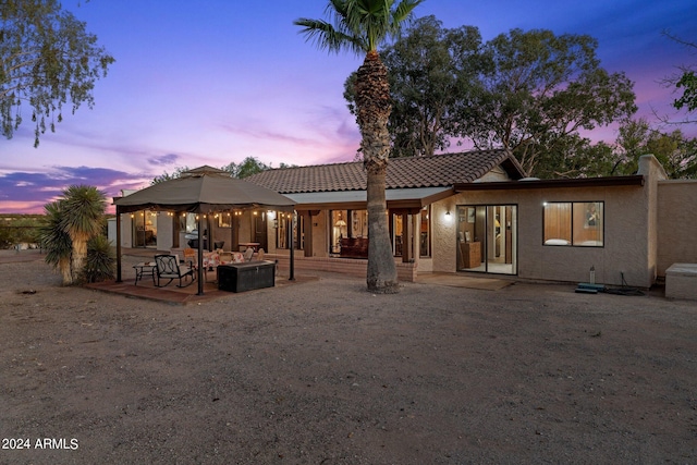 back house at dusk featuring a patio and outdoor lounge area