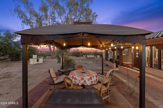 view of patio featuring outdoor dining space, fence, and a gazebo