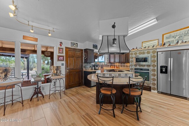 kitchen with rail lighting, dark brown cabinets, stainless steel appliances, backsplash, and decorative light fixtures