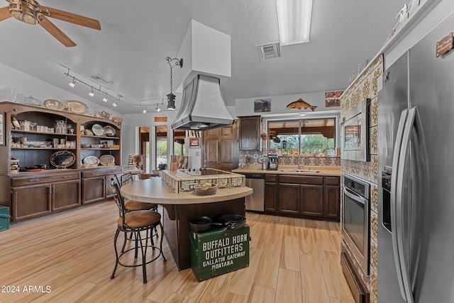 kitchen featuring visible vents, custom range hood, appliances with stainless steel finishes, light wood-style floors, and a sink