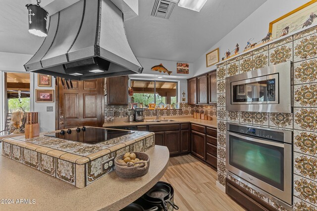 kitchen with range hood, visible vents, backsplash, appliances with stainless steel finishes, and a sink