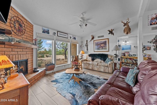 living area with lofted ceiling, a brick fireplace, ceiling fan, and visible vents