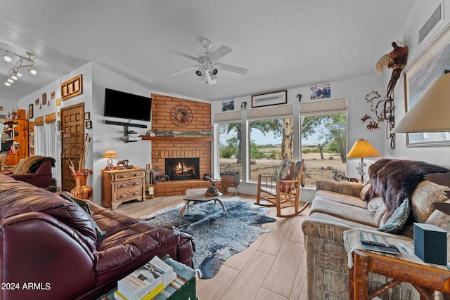 living area featuring a fireplace, wood finished floors, visible vents, a ceiling fan, and vaulted ceiling